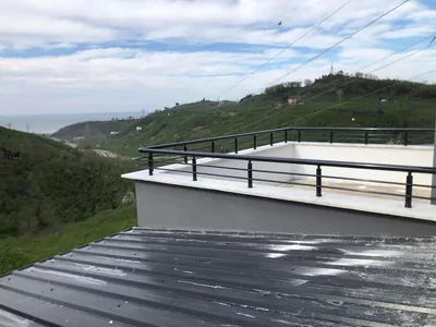 Beton parapet üstüne monte antrasit siyah alüminyum korkuluk, çatı terasını deniz manzarasına karşı çevreliyor