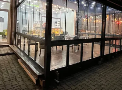 Pastanenin kaldırımdaki oturma alanı siyah profilli katlanır cam sistemle kapatılarak kış bahçesine çevrilmiş