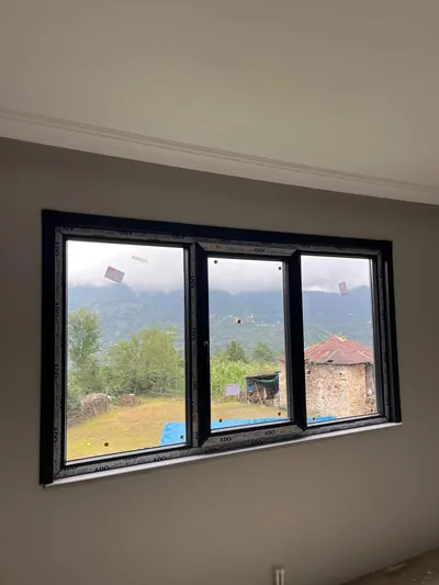 Antrasit renkli sürme PVC pencere, boyası bitmiş odada geniş dağ ve bahçe manzarasına açılıyor