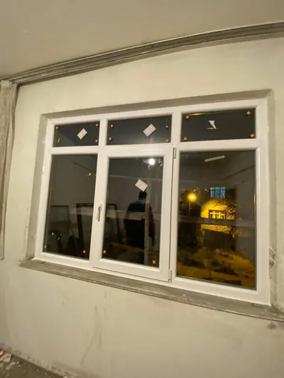 Beyaz PVC pencere, üst sabit cam kuşağı ve ortada açılır kanadıyla gece tamamlanmış montajda